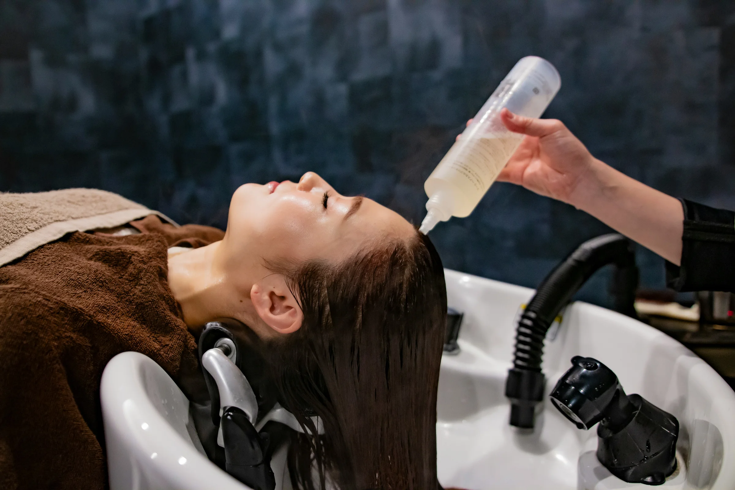 Stylist applying a hair treatment at the basin - repair and conditioning treatments at Characters Hair Randwick