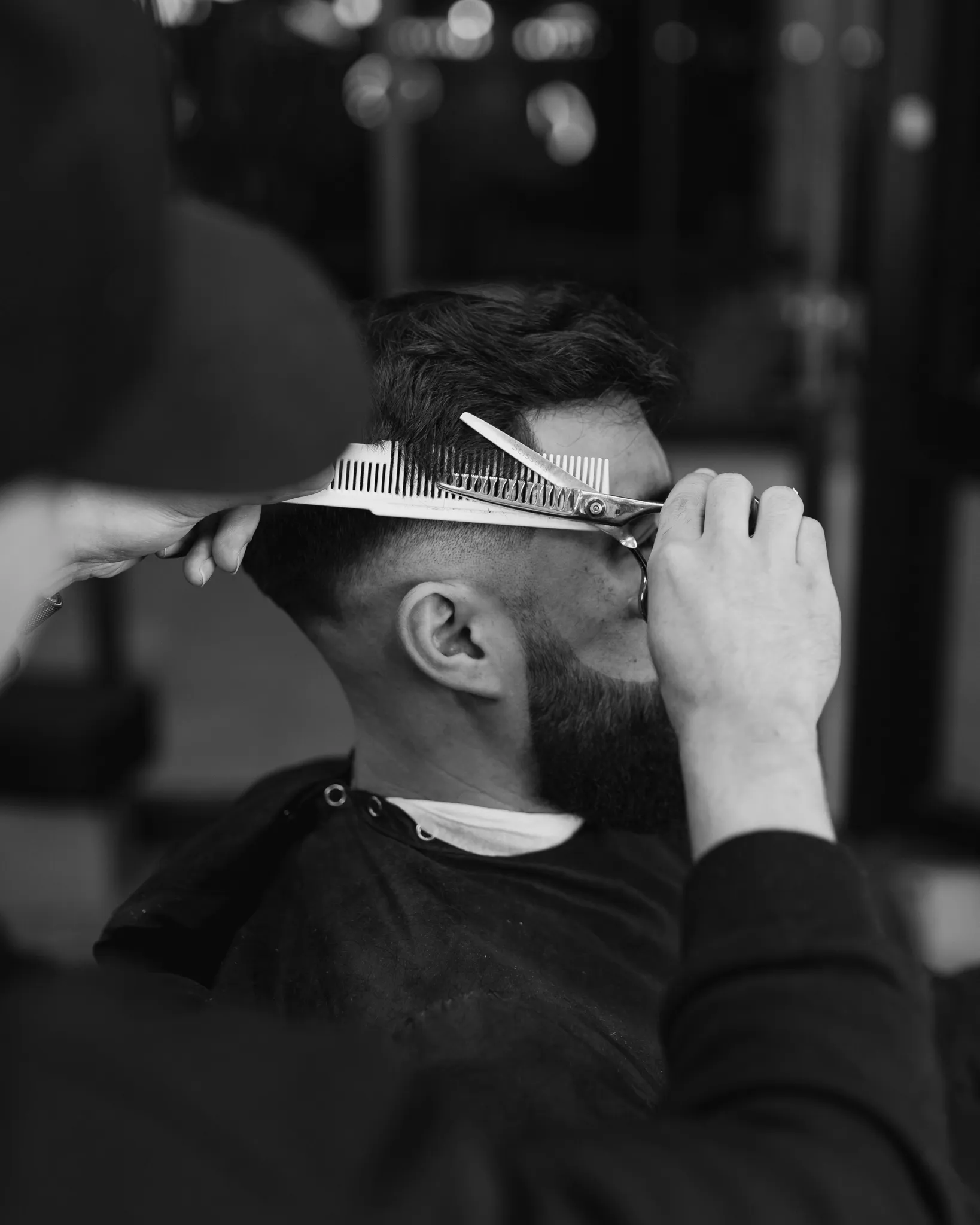 Stylist cutting scissor-over-comb into a men's short back and sides at Characters Hair, Randwick, Eastern Suburbs Sydney